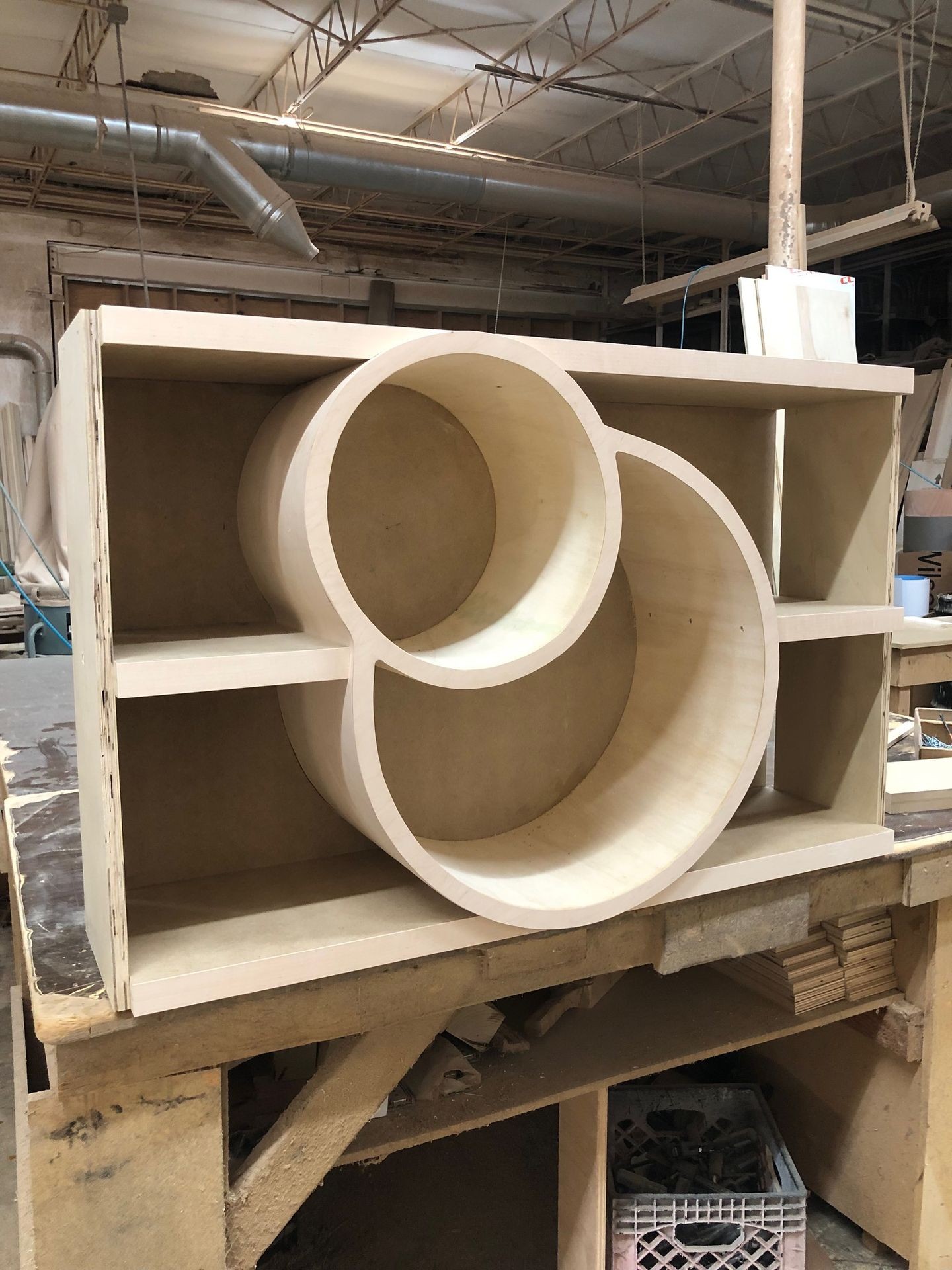 Wooden shelving unit with circular compartments on a workshop table.