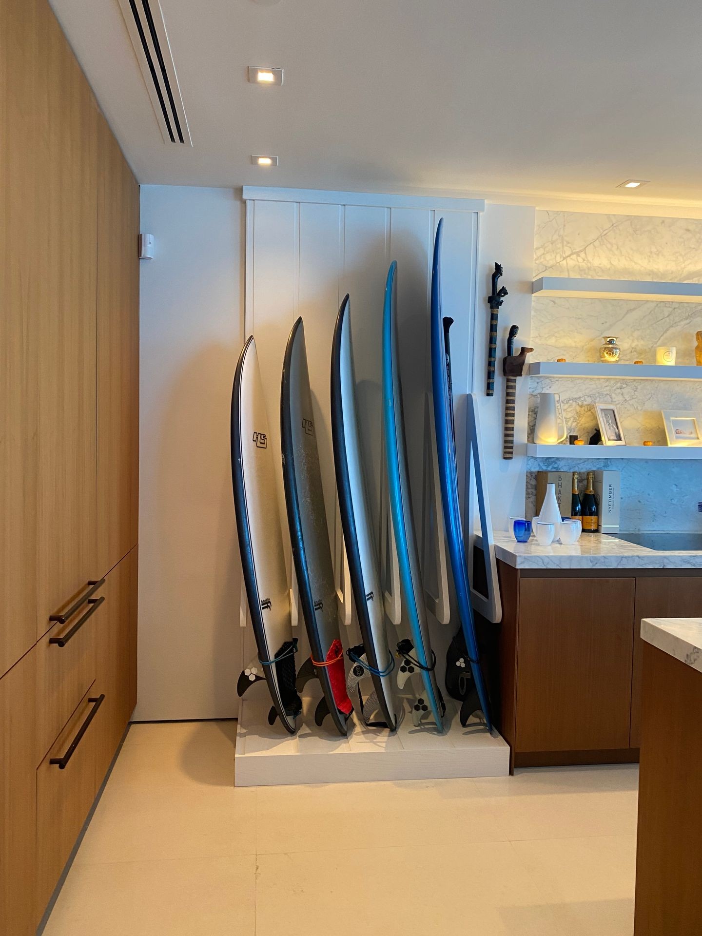 Indoor corner with a rack of surfboards and shelving displaying decorative items in a modern room.